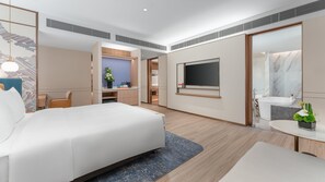 A modern hotel room with a large bed, a desk, a TV, and a bathroom with a bathtub and mirror. - Holiday Inn Express Shunde Daliang (Foshan)