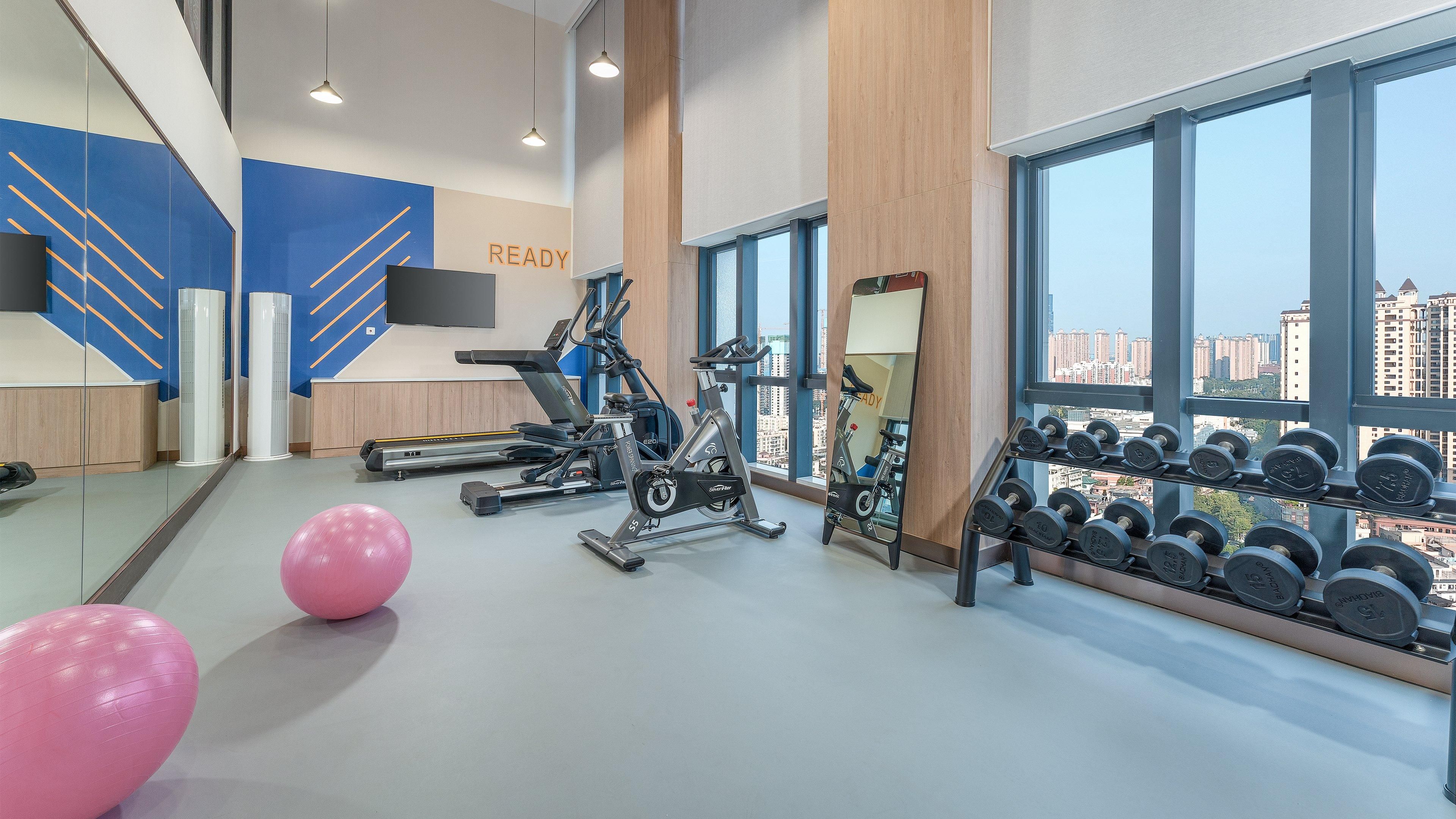Un gimnasio con equipo de ejercicio, un espejo y un estante con mancuernas.