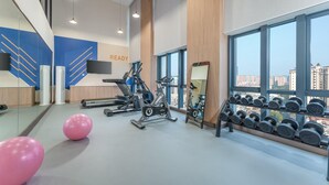 Un gimnasio con equipo de ejercicio, un espejo y un estante con mancuernas.