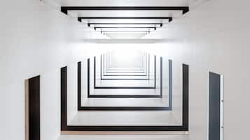 A modern interior with a geometric design, featuring a central corridor with a series of parallel lines and rectangular openings.