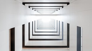A modern interior with a geometric design, featuring a central corridor with a series of parallel lines and rectangular openings. - Holiday Inn Express Shunde Daliang (Foshan)