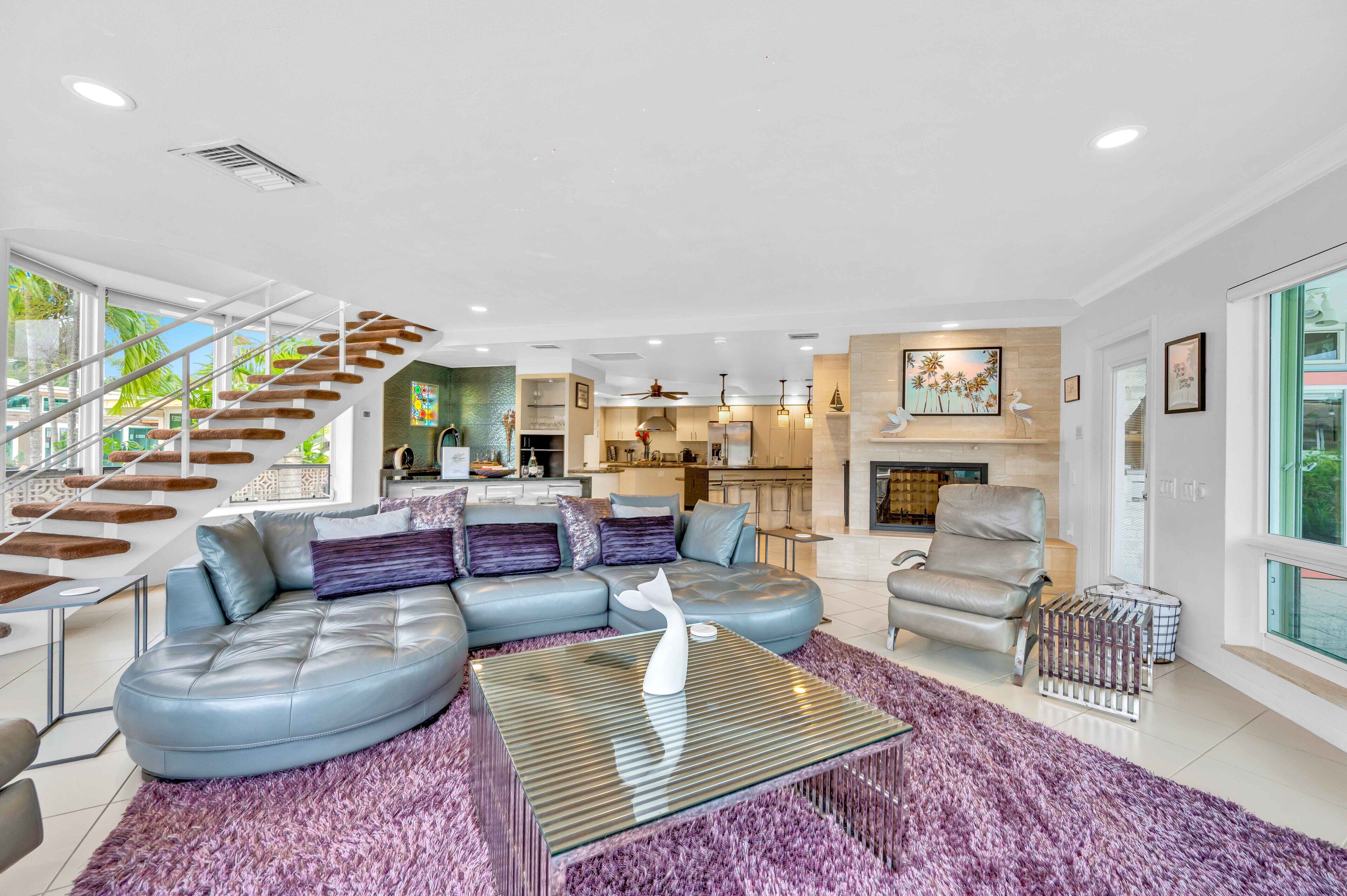A modern living room with a curved sofa, a glass coffee table, and a staircase leading to an upper level.