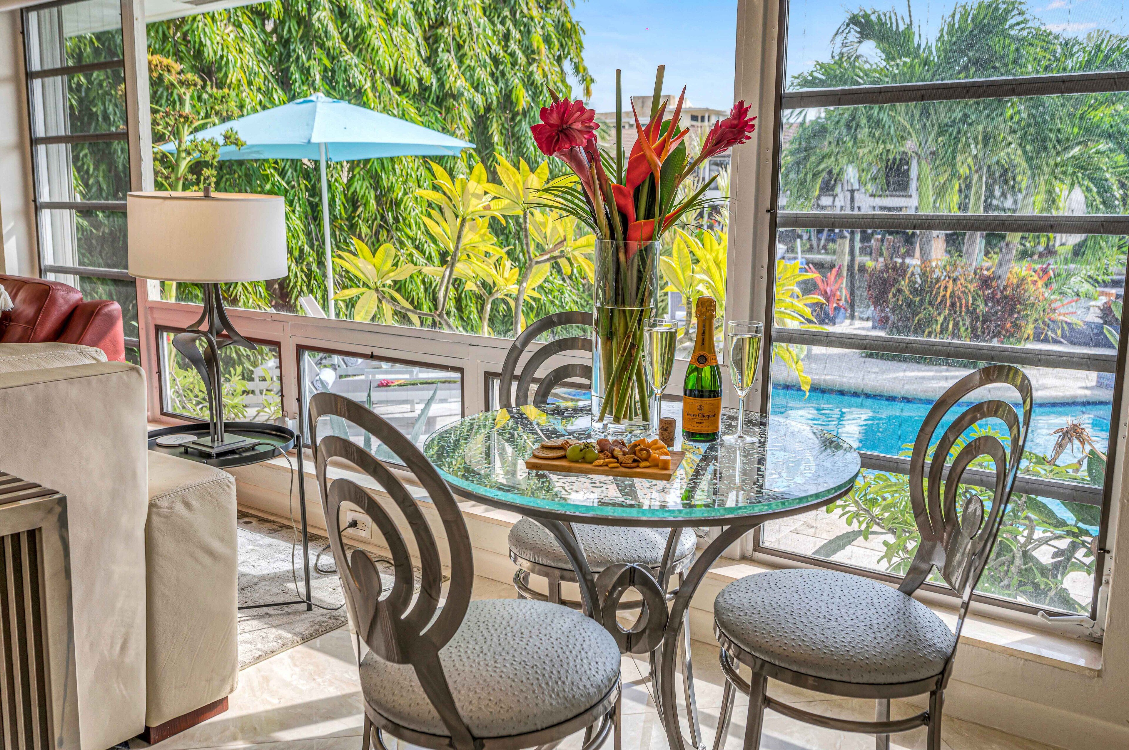A glass table with a bottle of champagne, a glass, and a fruit platter.