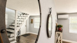 Une pièce avec un grand miroir, un vélo, un escalier et un appareil de climatisation.