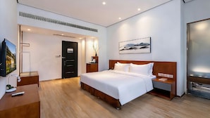 Habitació d'hotel moderna amb un llit gran, un escriptori, un televisor i una porta.