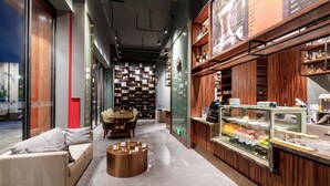 Un interior modern amb zona de seients, una vitrina amb productes alimentaris i una paret amb un menú.