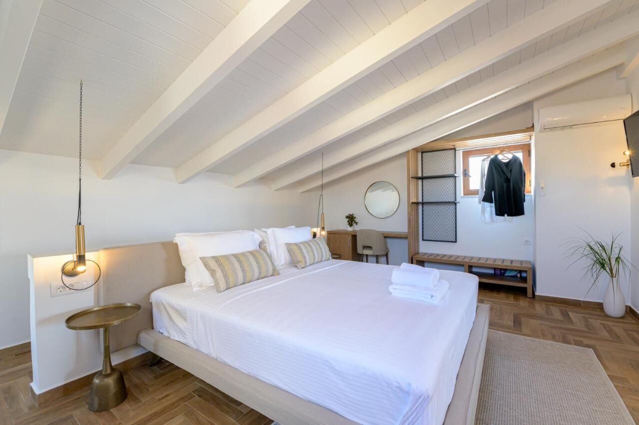 A bedroom with a large bed, bedside tables, a hanging light fixture, a round mirror, and a small desk with a chair.