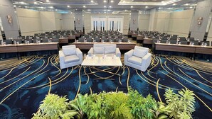 Une salle de conférence dotée de plusieurs tables, de chaises et d’un espace de sièges central.
