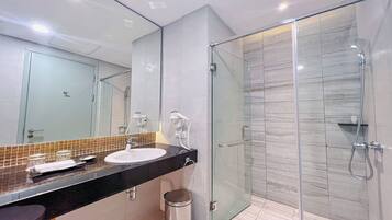 A modern bathroom with a glass-enclosed shower, a large mirror, and a black countertop.