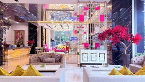 Un hall d’hôtel moderne doté d’un espace salon central, d’un comptoir d’accueil et d’une grande fenêtre donnant sur l’intérieur.