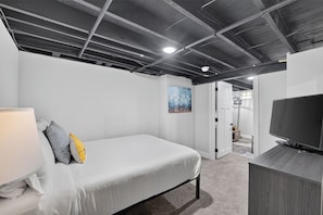 A modern bedroom with a bed, a television, and a painting on the wall.