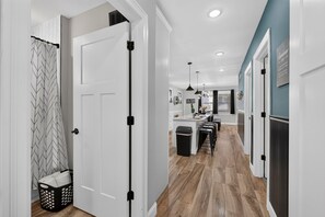 A hallway with a white door, a laundry basket, and a black trash bin.