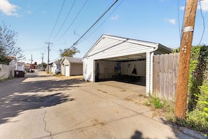 A residential garage with a wooden fence, a clear sky, and utility poles.