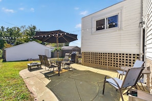 Eine Terrasse mit Gartenmöbeln, einem Grill und einer Lichterkette.