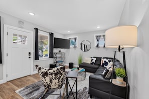 A modern living room with a sofa, a chair, a coffee table, a TV, and a lamp.