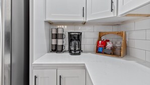 Une cuisine avec des meubles blancs, une machine à café et un étagère à épices.