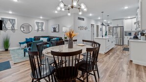 Une cuisine moderne avec des meubles blancs, un îlot central et un coin repas comprenant une table ronde et des chaises.