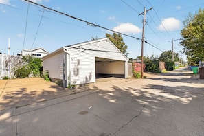 A single-story garage with a sloped roof, a concrete driveway, and a fenced yard.