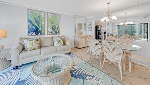 Ein modernes Wohnzimmer mit einer Couch, einem Esstisch mit Stühlen und einer Küche im Hintergrund.
