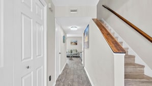 A hallway with a wooden staircase, white walls, and a tiled floor. - Southbay by the Gulf 12 Overlooking Pool! ~ Short Walk to Beach! (Destin)