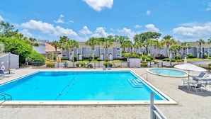 A swimming pool area with two pools, surrounded by a fence, and adjacent to a row of apartment buildings. - Southbay by the Gulf 12 Overlooking Pool! ~ Short Walk to Beach! (Destin)