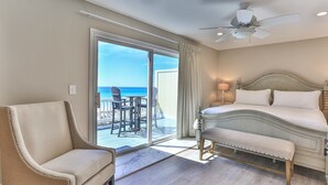 A hotel room with a bed, a chair, a desk with chairs, a ceiling fan, and a view of the ocean. - Completely Renovated 3-Bedroom Beach Front Townhome in Destin! (Destin)