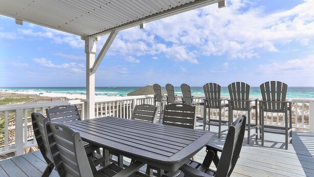 A covered outdoor seating area with a view of the beach and ocean.