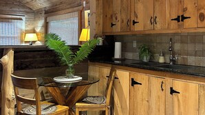 A rustic kitchen with wooden cabinets, a round glass table, and chairs. - Guest house close to Blue Mountain, Wasaga Beach and Collingwood!  (Nottawa)