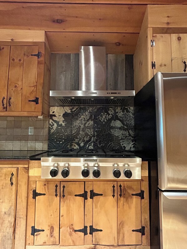 Une cuisine avec des meubles en bois, une cuisinière en acier inoxydable et un réfrigérateur.
