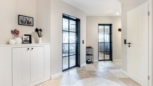 Ein moderner Flur mit einem weißen Schrank, einem gerahmten Bild und einer Glastür, die auf einen Balkon führt.