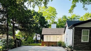 A paved driveway leading to a house with a stone facade and a wooden deck.