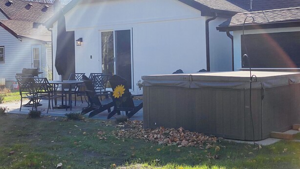 A house with a covered patio, a hot tub, and a lawn with scattered leaves. - Updated Home- Only a few minutes walk to Downtown Lake Geneva!! (Lake Geneva)