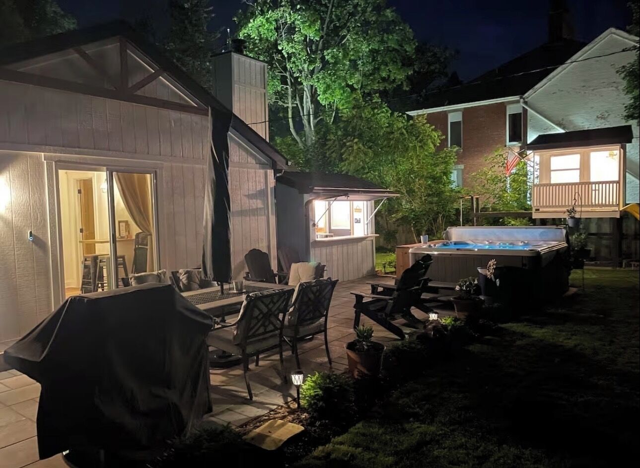 Un jardin avec un jacuzzi, des meubles de patio et un espace salon abrité.