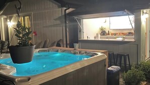 A hot tub in a backyard with a wooden deck, a small bar area, and potted plants. - Updated Home- Only a few minutes walk to Downtown Lake Geneva!! (Lake Geneva)