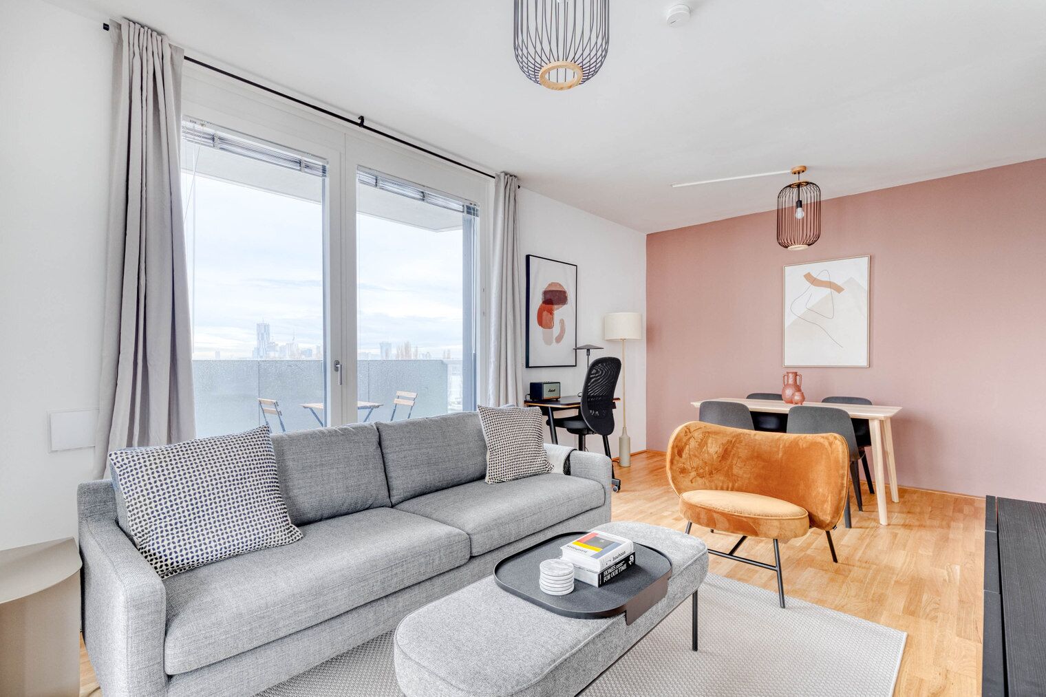Un salon moderne avec un canapé gris, une petite table basse et un coin repas comprenant une table et des chaises.