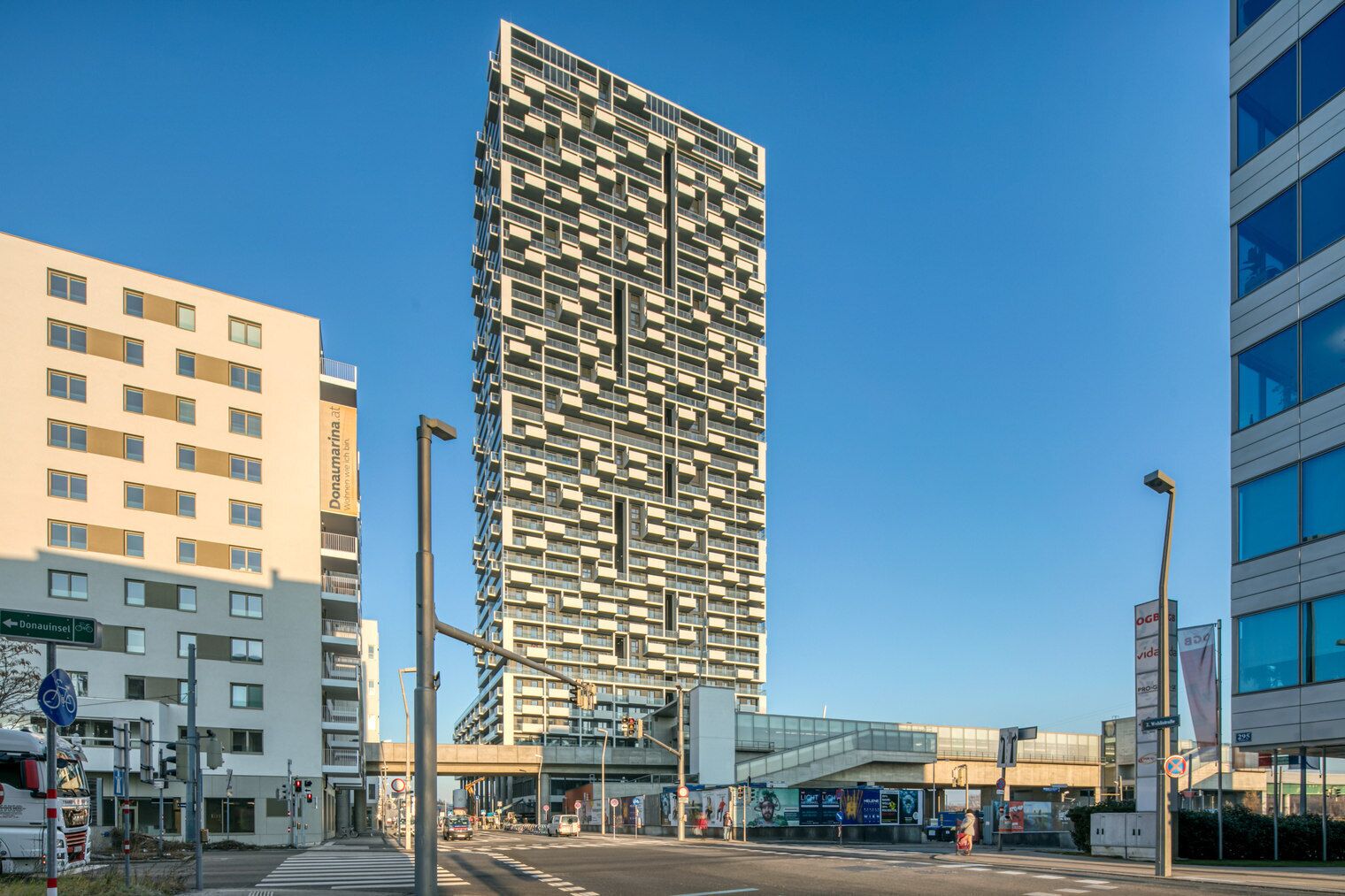 A modern high-rise building with a unique facade, surrounded by urban infrastructure.