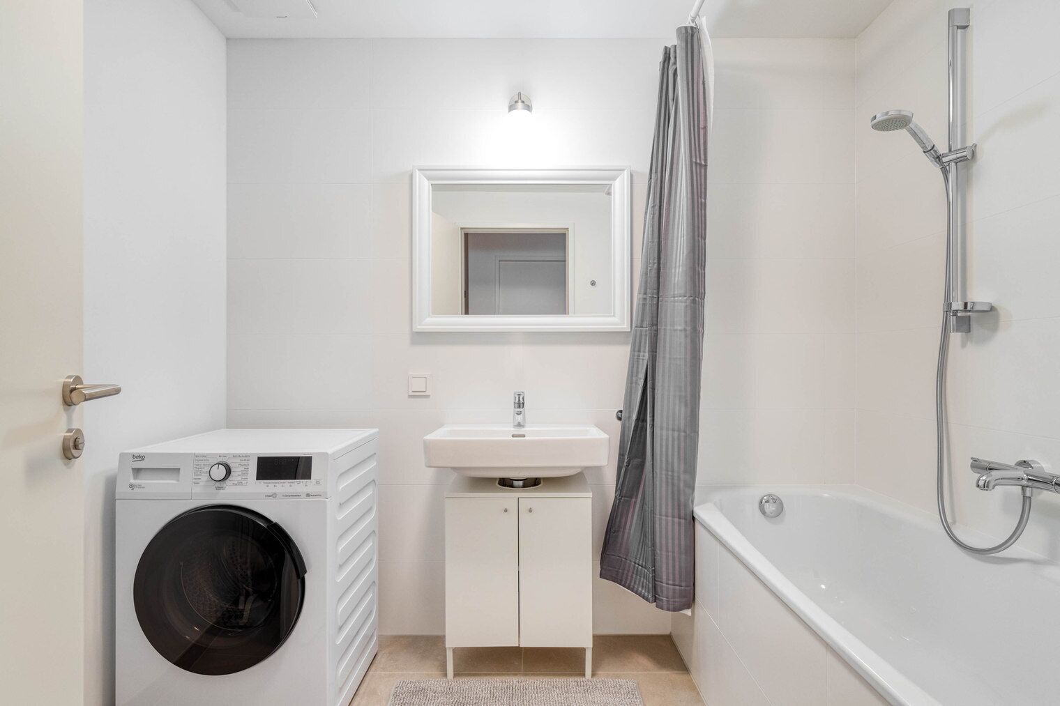 Ein modernes Badezimmer mit Waschmaschine, Waschbecken, Spiegel und Dusche.