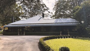 Um edifício com telhado de metal corrugado, cercado por sebes bem cuidadas e gramado aparado.