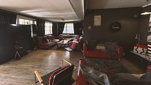 Een woonkamer met een bank, stoelen, een salontafel en een televisie.