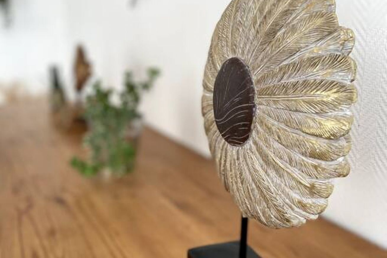 Un abanico decorativo con diseño de hoja sobre un soporte.
