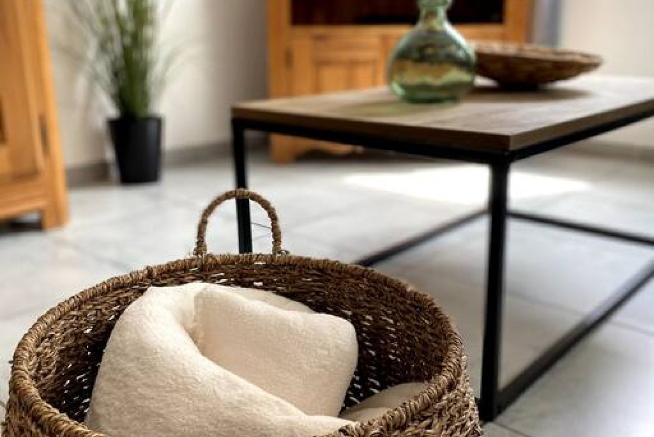 Un panier en osier avec un coussin blanc posé sur une table en bois.