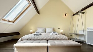 Une chambre avec un plafond en pente, un lit avec deux oreillers, des lampes de chevet et une échelle suspendue.