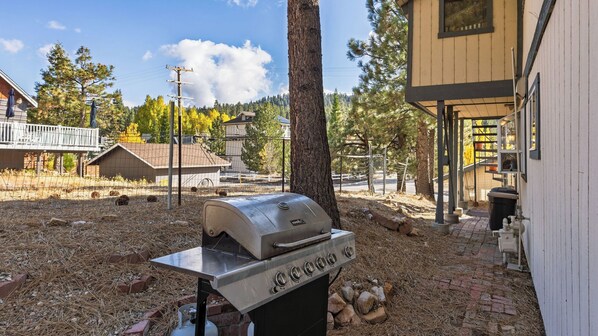 A barbecue grill in a backyard with a house, trees, and a fence. - 50 Yards to Lake, Boulder Bay Pool Table Lakeside in Bearadise by Avantstay (Big Bear Lake)