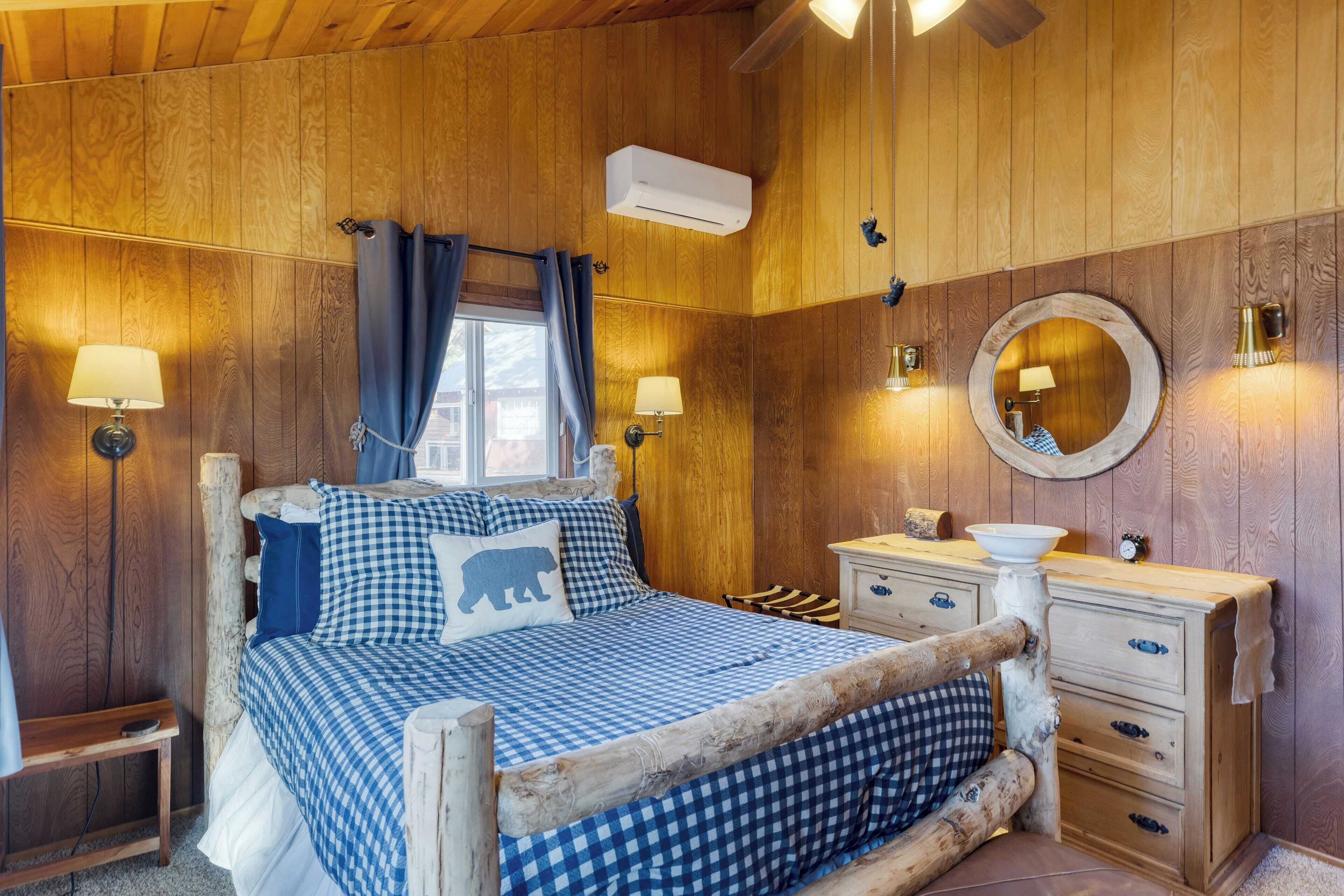 A wooden cabin bedroom with a bed, dresser, and a round mirror.