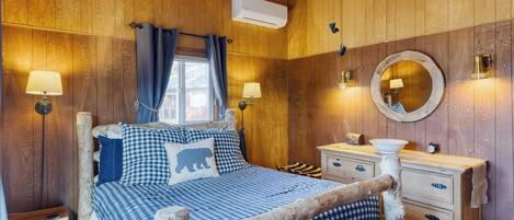 A wooden cabin bedroom with a bed, dresser, and a round mirror.