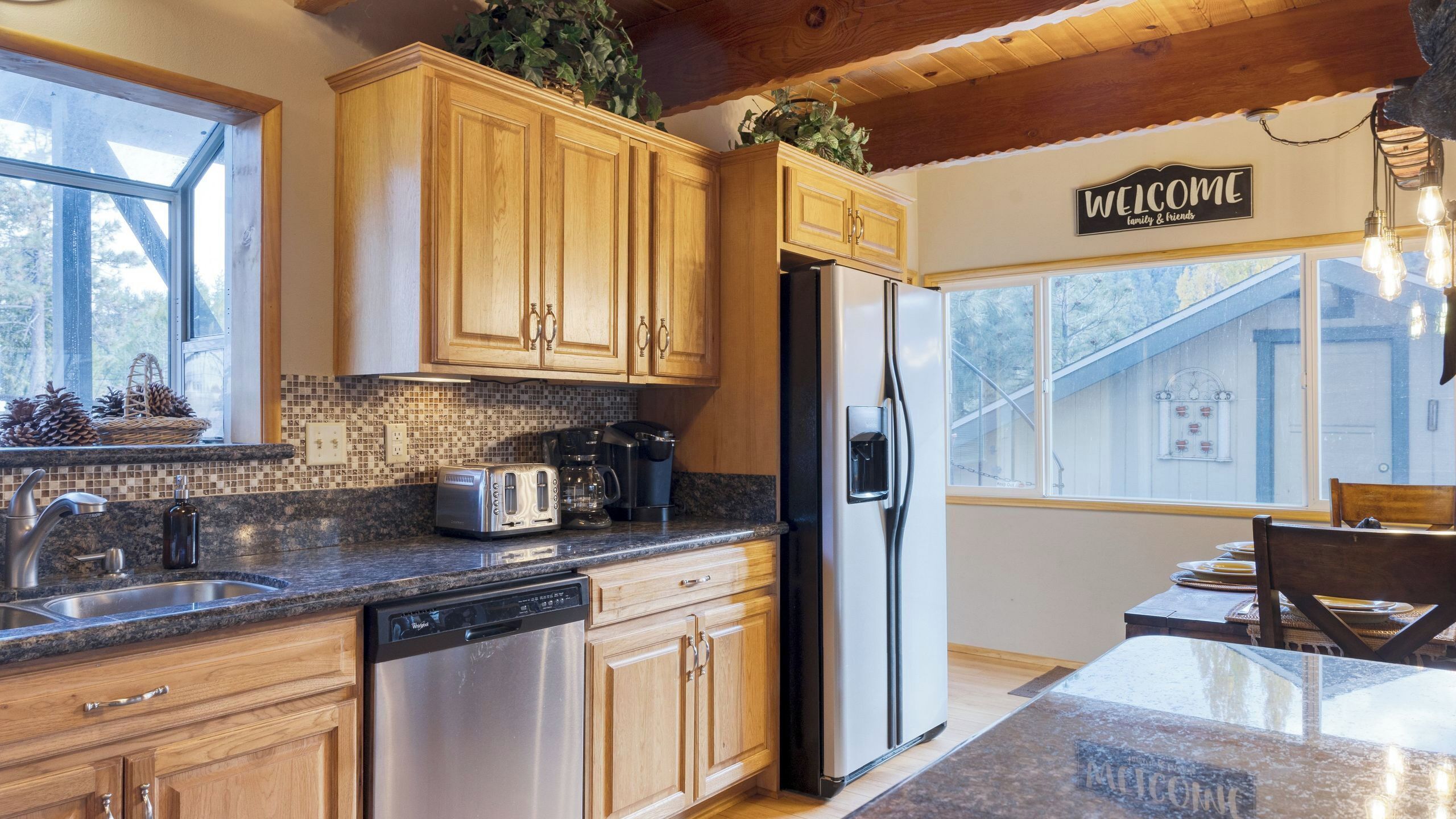 A kitchen with wooden cabinets, a stainless steel refrigerator, a dishwasher, a toaster, and a coffee maker.