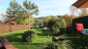 Un giardino curato con diverse piante e una sedia rossa.