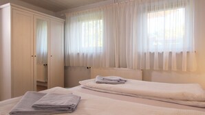 Una camera da letto con due letti, un armadio e tende leggere alle finestre.