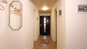 Un corridoio con pavimento in legno, una porta in fondo e un quadro appeso al muro.