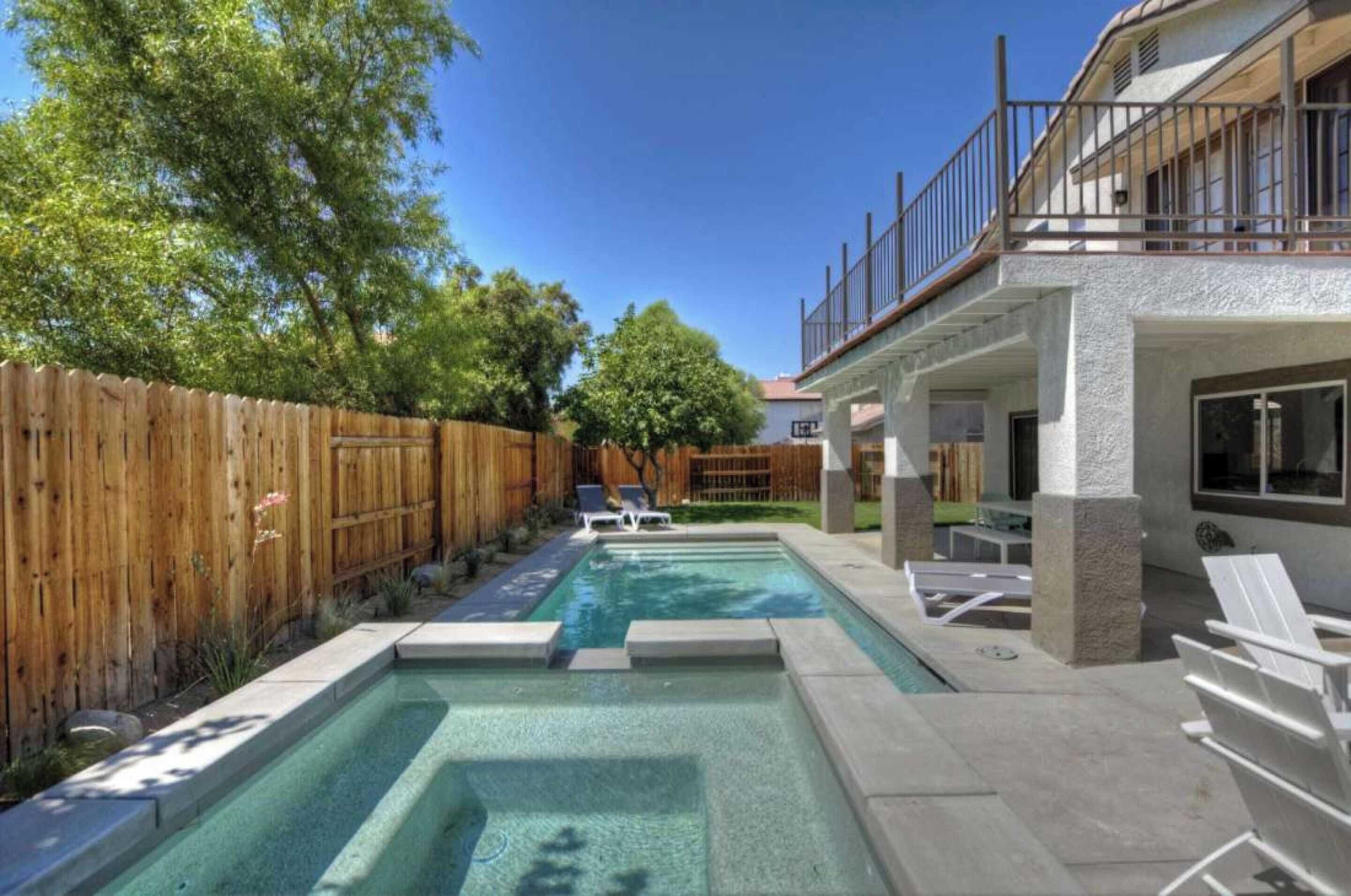 A backyard with a swimming pool, wooden fence, and outdoor seating area.